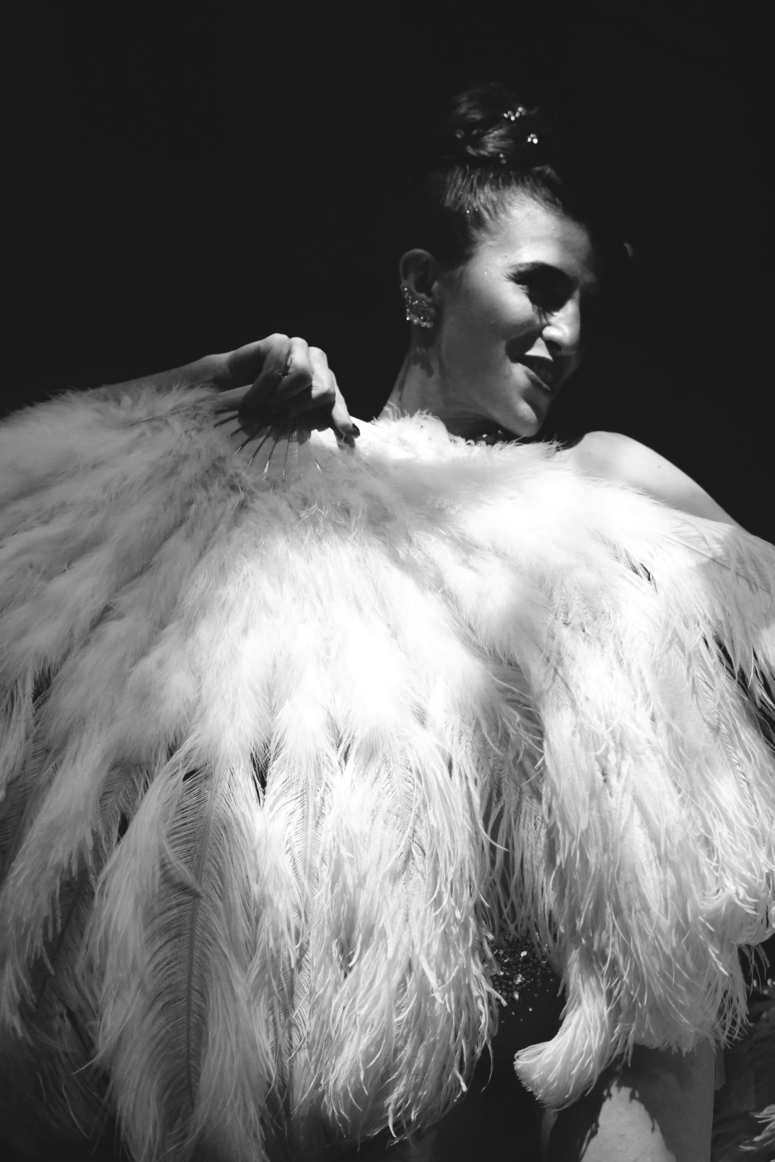 A cabaret performer in a black and white picture wearing a feather gown.